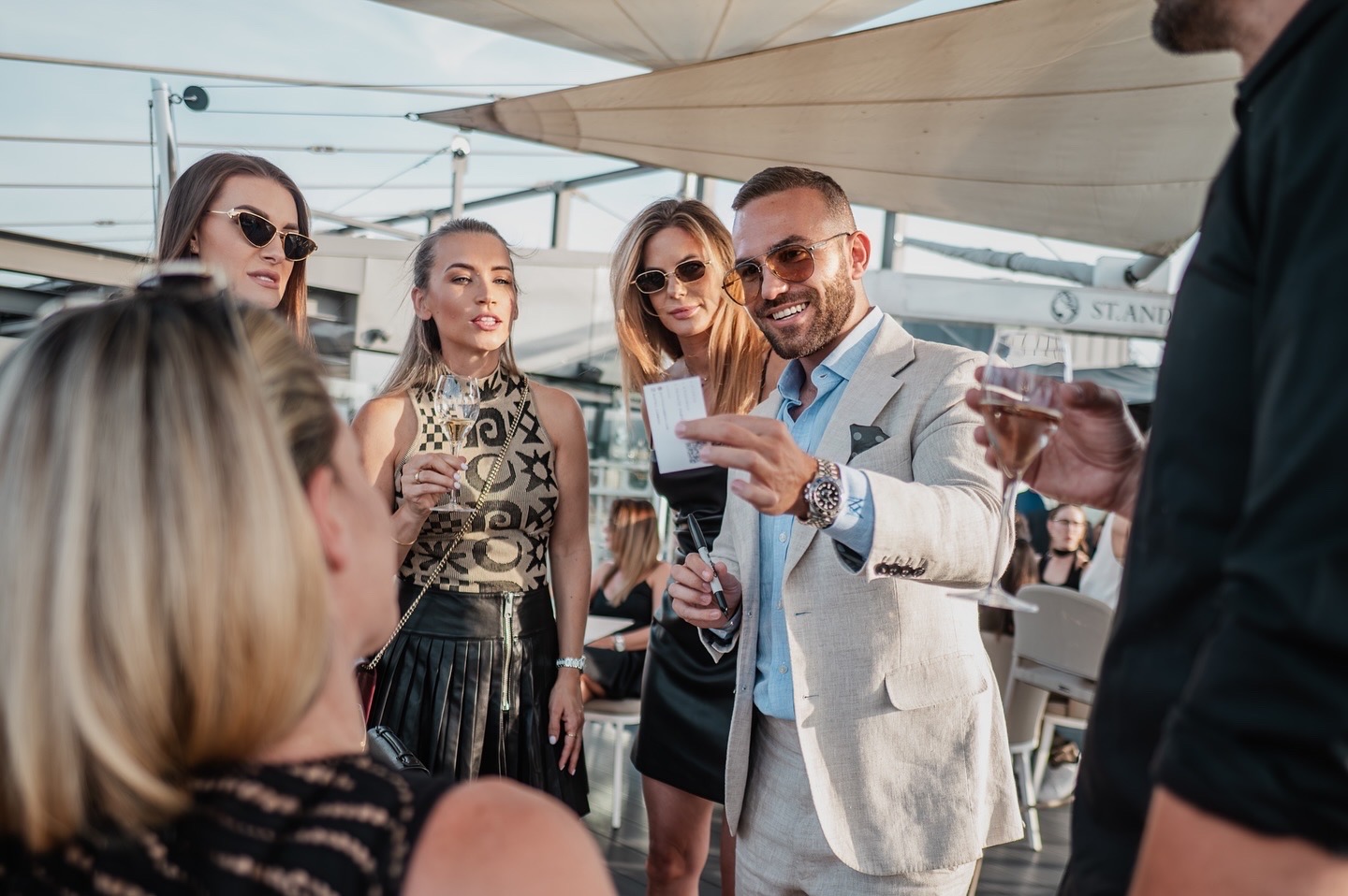 Guests gathered at a luxury cocktail reception while Matteo Cammisa performs close-up magic with playing cards