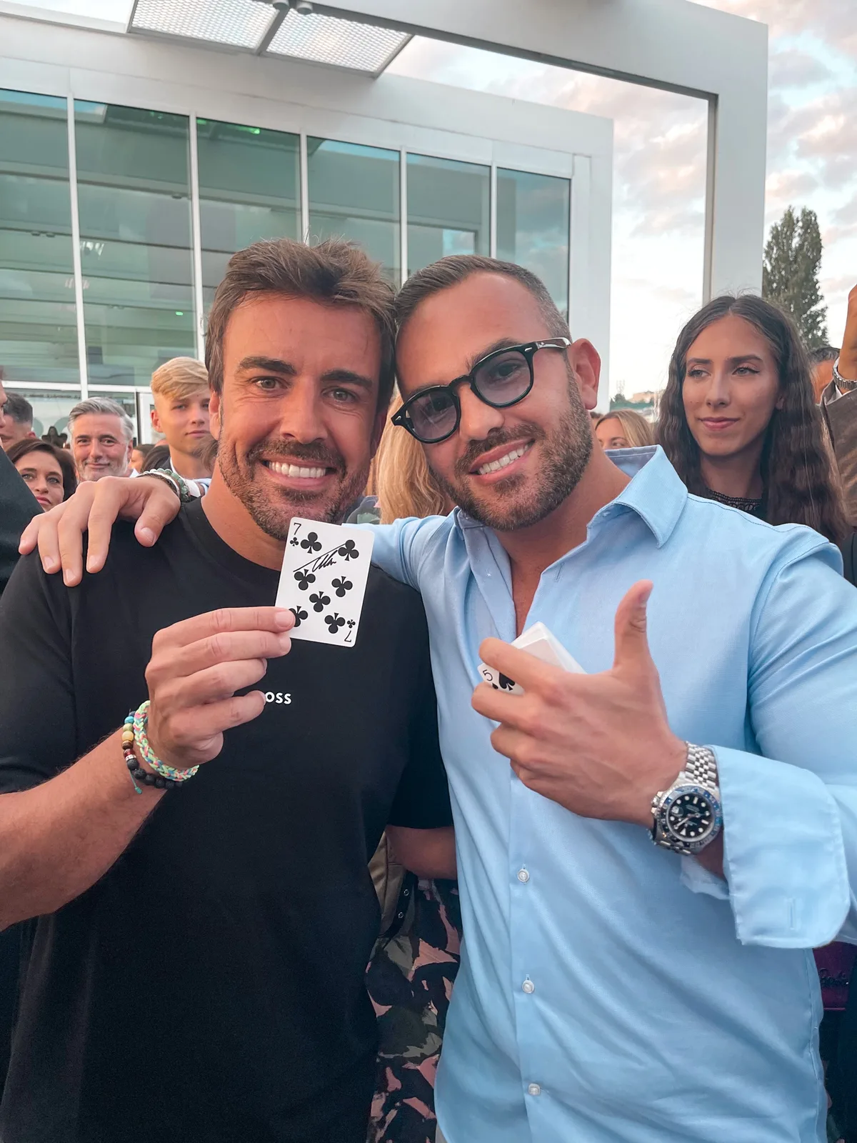 Fernando Alonso holding a signed seven of clubs beside magician Matteo Cammisa