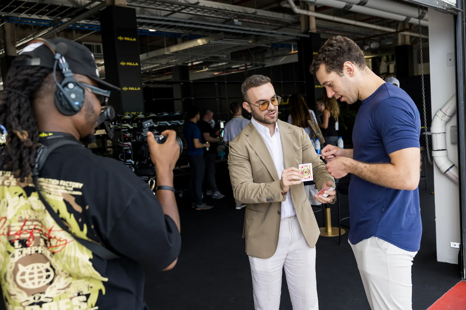 Matteo Cammisa performing a card effect for a guest while a videographer films in the Miami garages