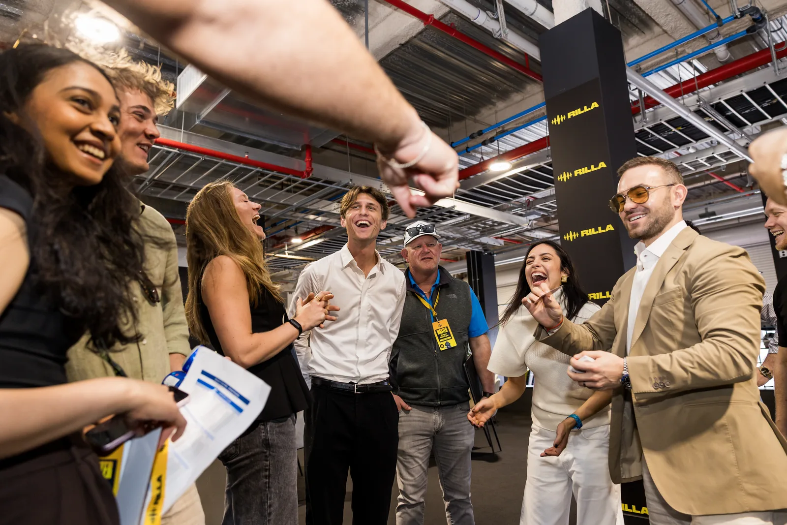 A group of guests laughing during Matteo Cammisa's close-up magic in the garages at the Miami International Autodrome