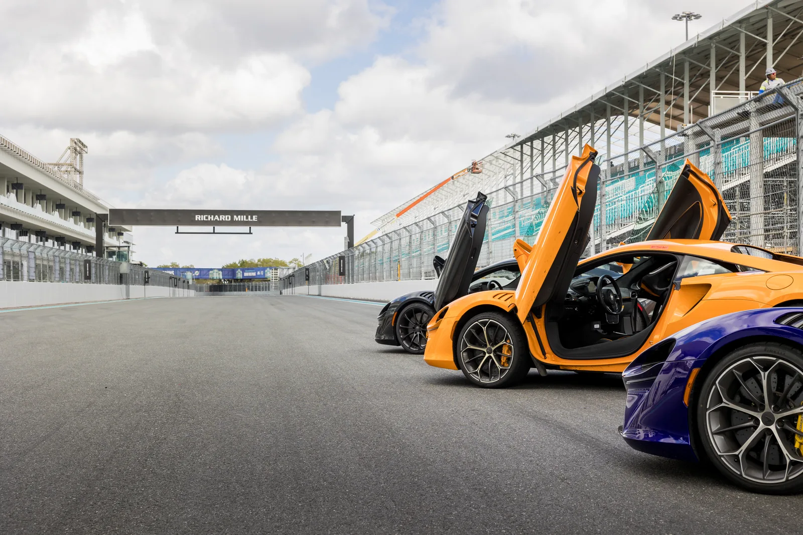 An orange McLaren with its doors up parked on the start-finish straight of the Miami International Autodrome