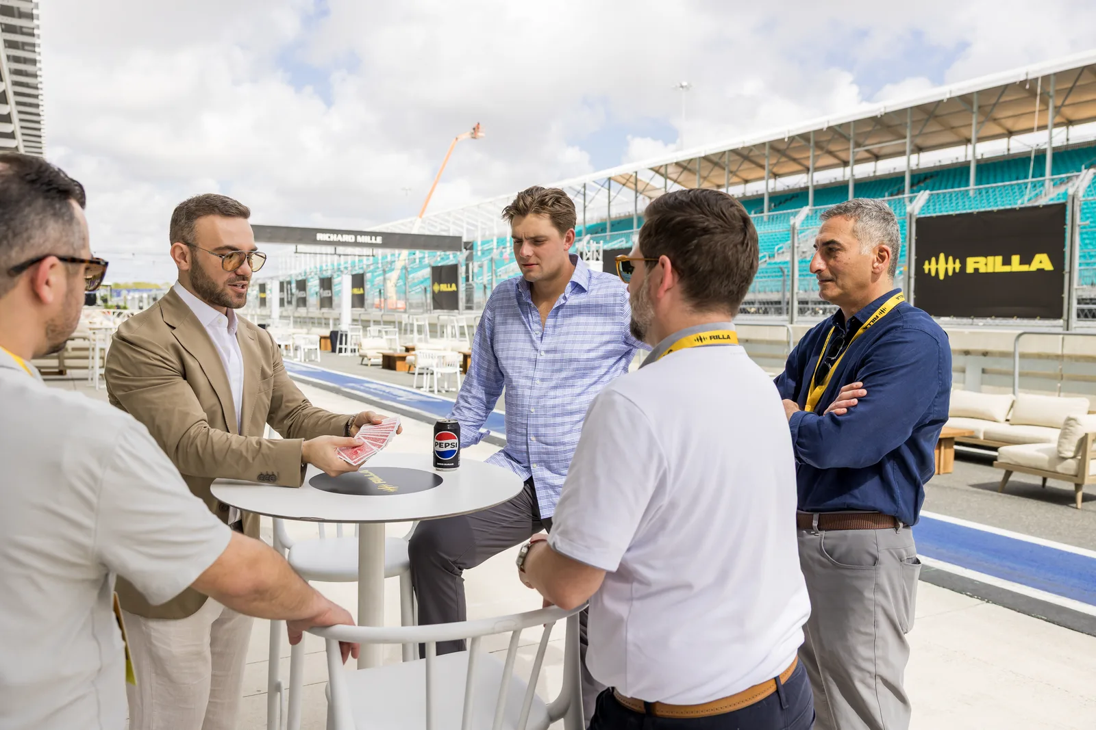 Matteo Cammisa performing a card effect for guests standing at a paddock table at the Miami International Autodrome