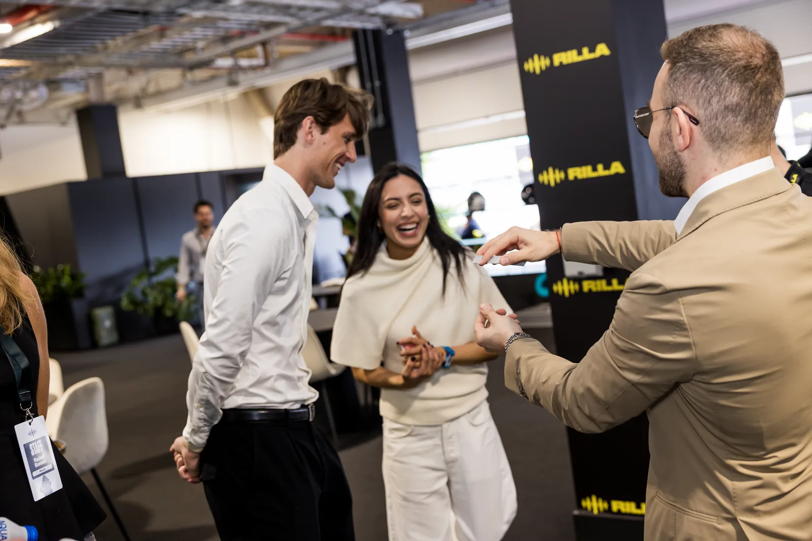 Guests smiling and reacting as Matteo Cammisa performs close-up magic in a Miami race-week hospitality suite