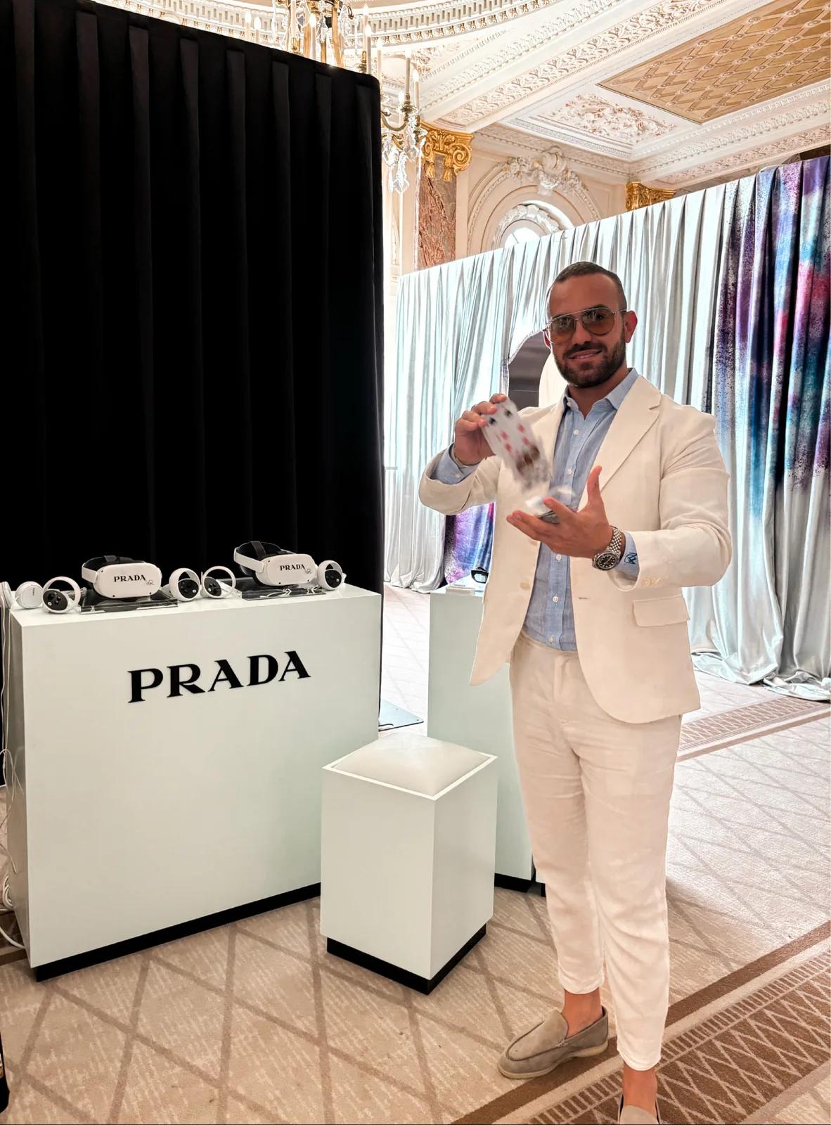 Matteo Cammisa performing a card flourish beside a Prada display in the gilded Carlton Cannes ballroom