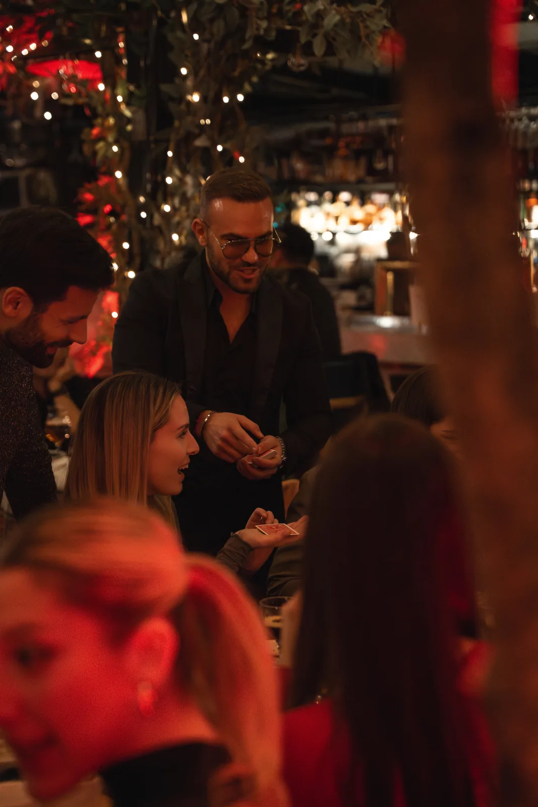 Matteo Cammisa performing a card trick for guests among fairy lights at the Eataly rooftop in New York City